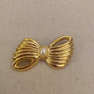 AAI: marked. Vintage gold tone ribbon bow brooch with a faux pearl in the middle